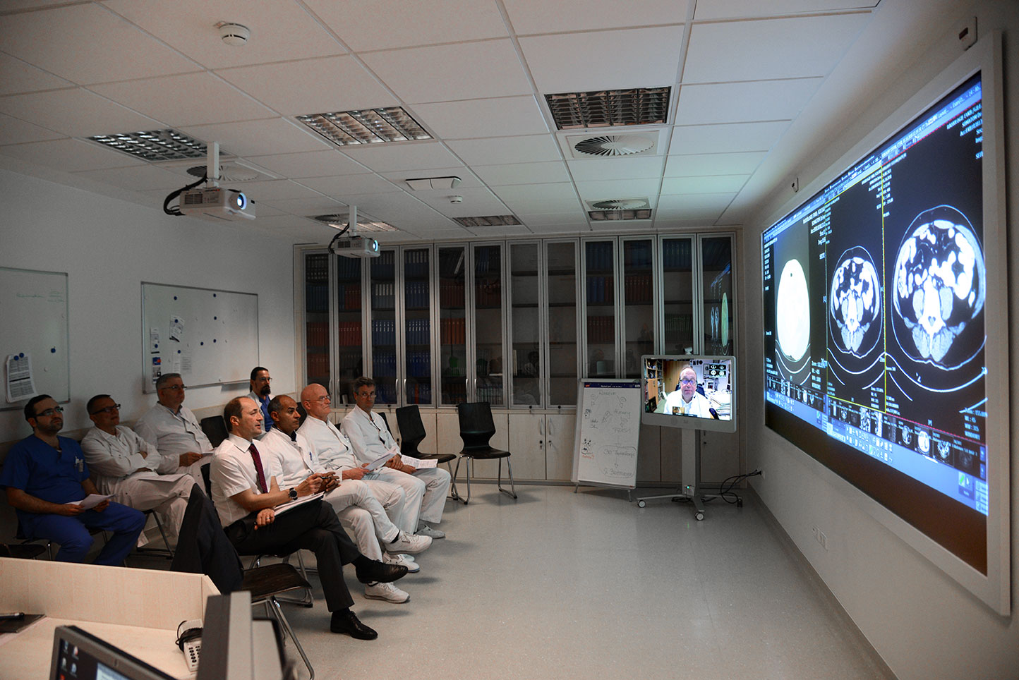 ÄrztInnen aus verschiedenen Fachbereichen gucken sich gemeinsam auf einem großem Bildschirm radiologische Aufnahmen an.