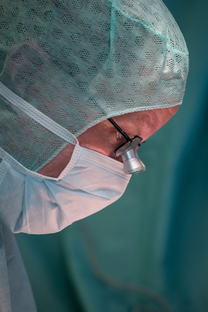 Seitlichen Portrait von einem Arzt, während dieser konzentiert auf die operations Wunde schaut.