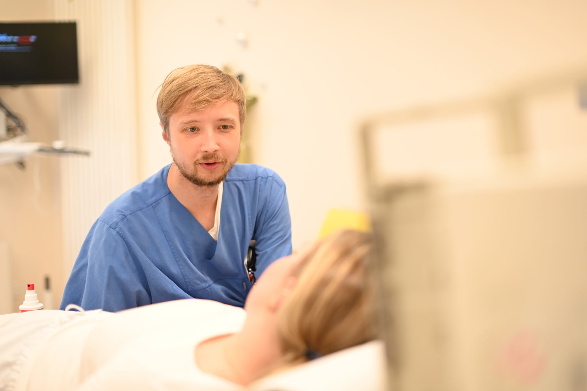 Eine Pflegekraft im Gespräch mit einem Patienten am Patientenbett.